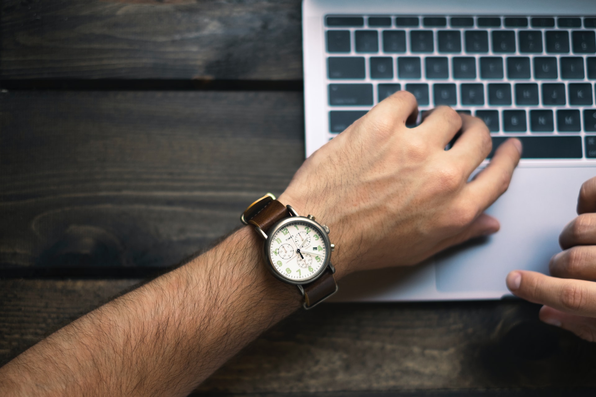 A man&rsquo;s wristwatch beside a laptop, indicating a product launch on time