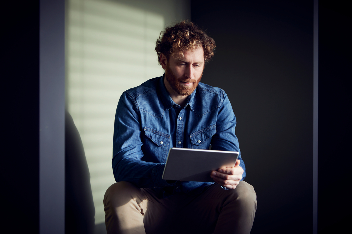 Casual businessman sitting down using a tablet to shop e-commerce
