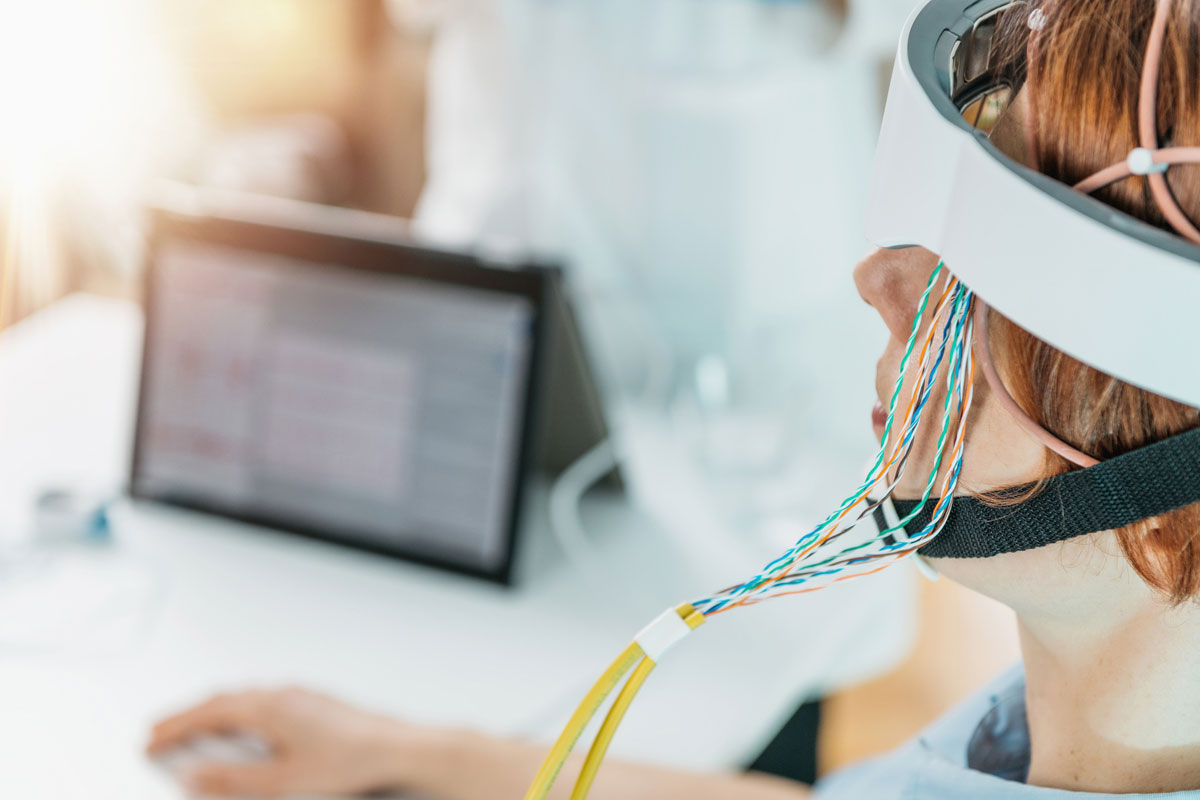 Woman with a wired neuro cap on her head being monitored