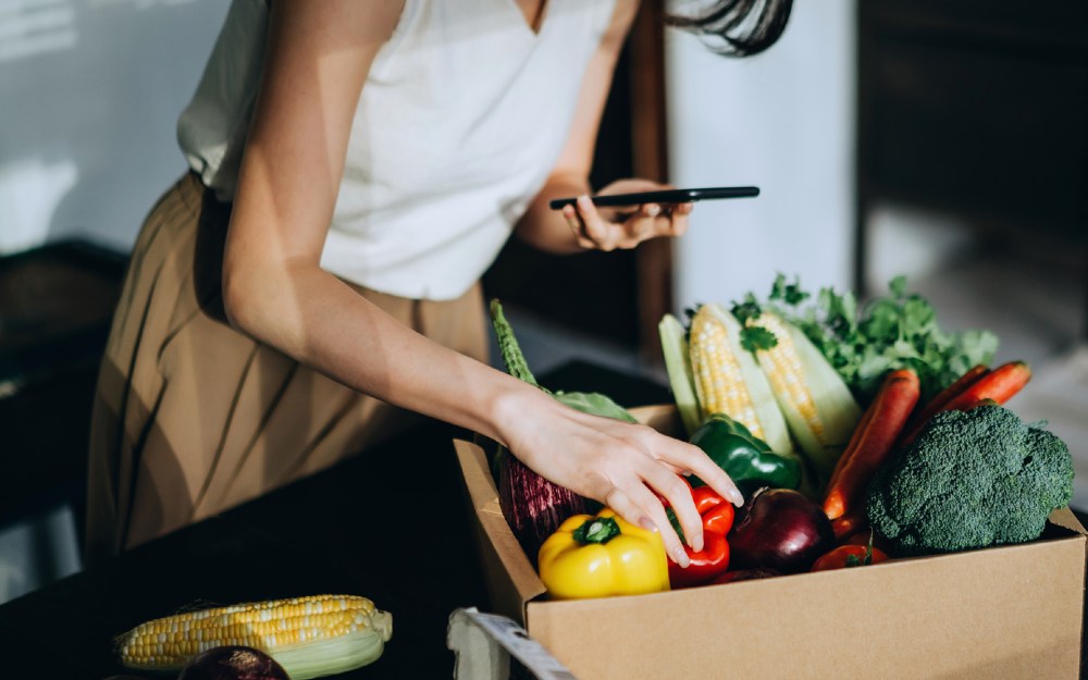 woman with phone checking online grocery order
