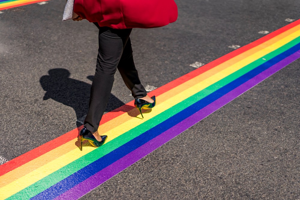 Legs of woman crossing the street on LGBT stripe