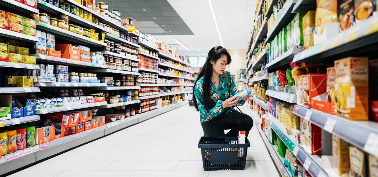 Asian woman kneeling in an aisle looking at a product
