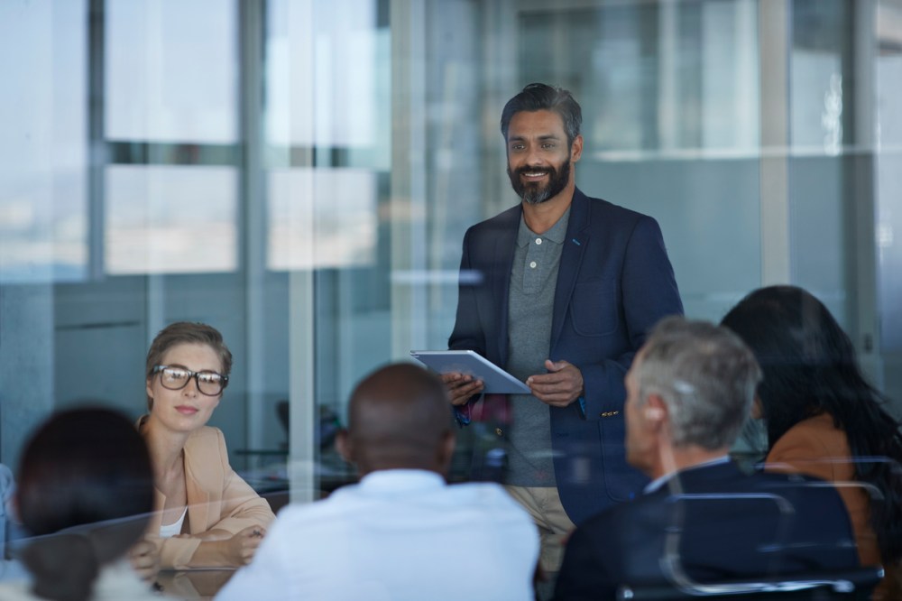 Business people talking together in large glass conference room
