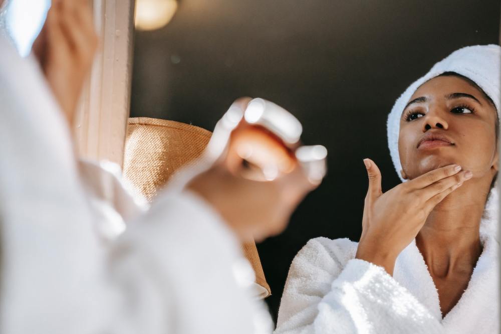 Woman applies clean beauty product in front of mirror