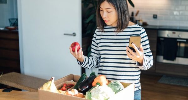 Young woman ordering groceries online with smartphone