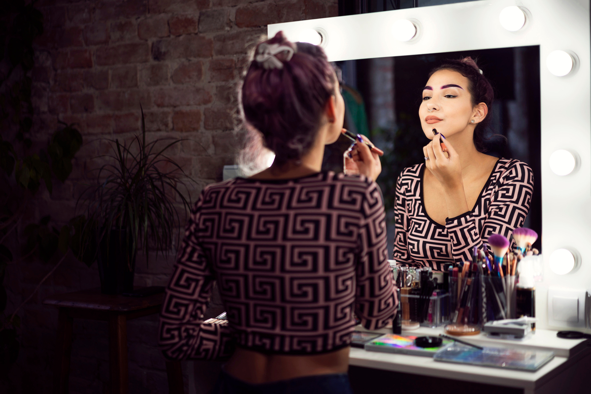 A young woman uses a personalized beauty product in front of a mirror