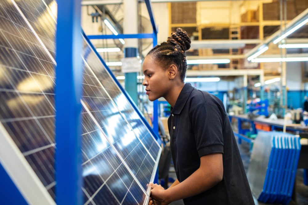 Woman inspects a solar panel to help fight the changing climate