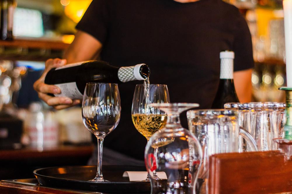 A bar tender pours wine at an on-premise location