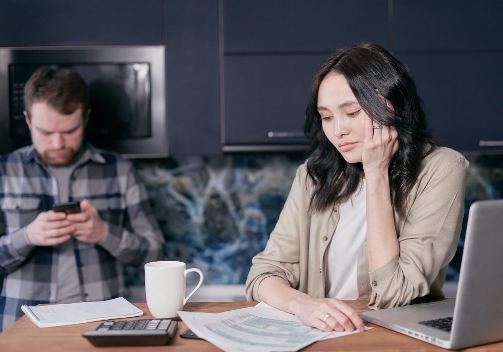 A worried couple makes a budget at a coffee table to respond to rising interest rates.