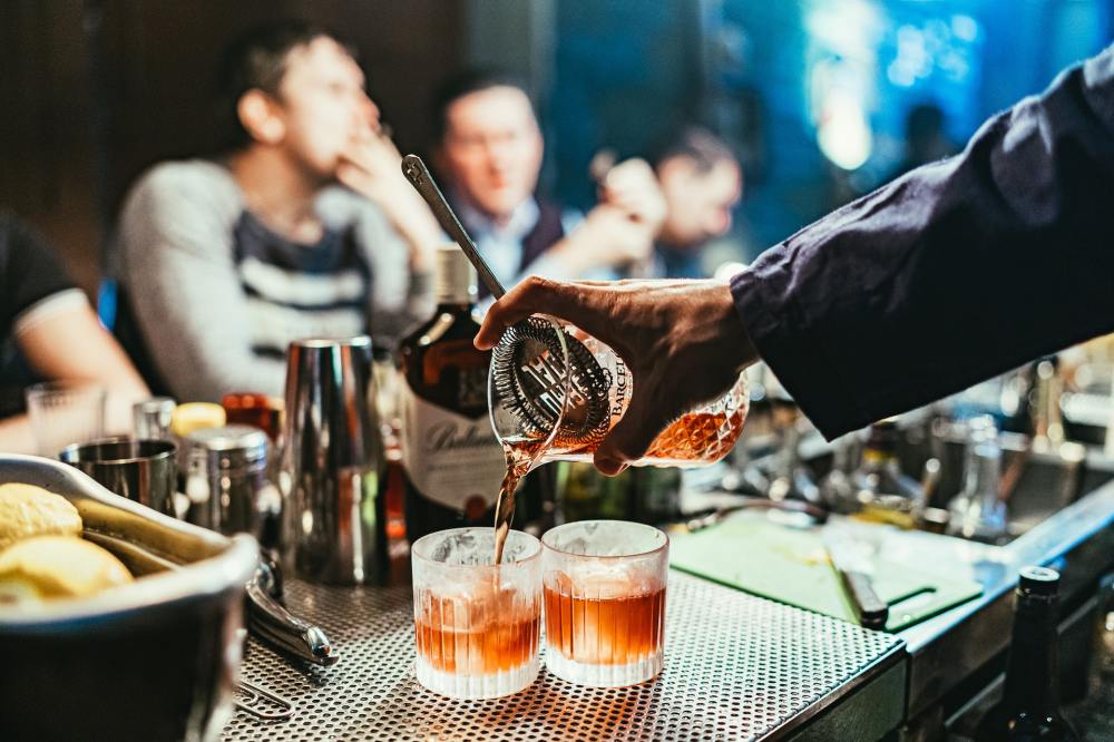 A bartender pours two glasses of alcoholic beverages on-premise.