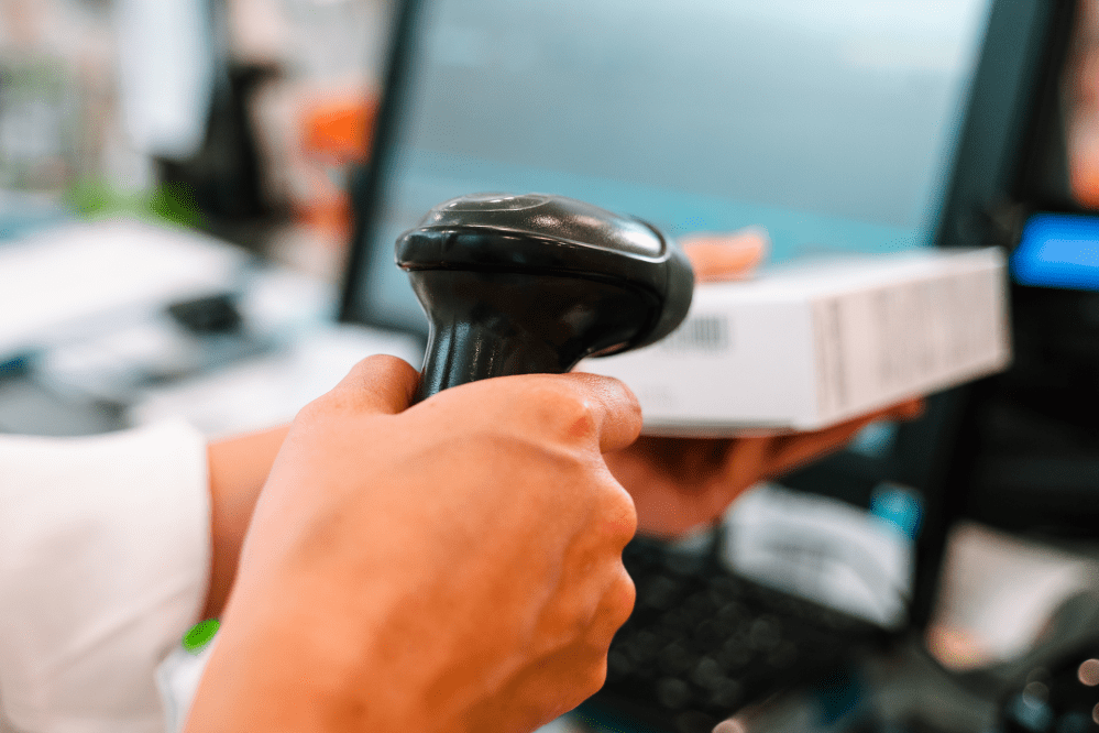 Male hand holding a price scanner up to the barcode on a package at checkout