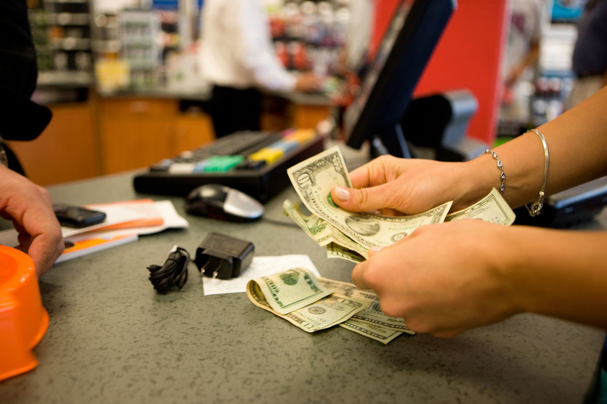 Female hands paying for an item with cash at a cash register