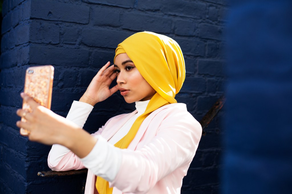 Young Muslim woman using phone