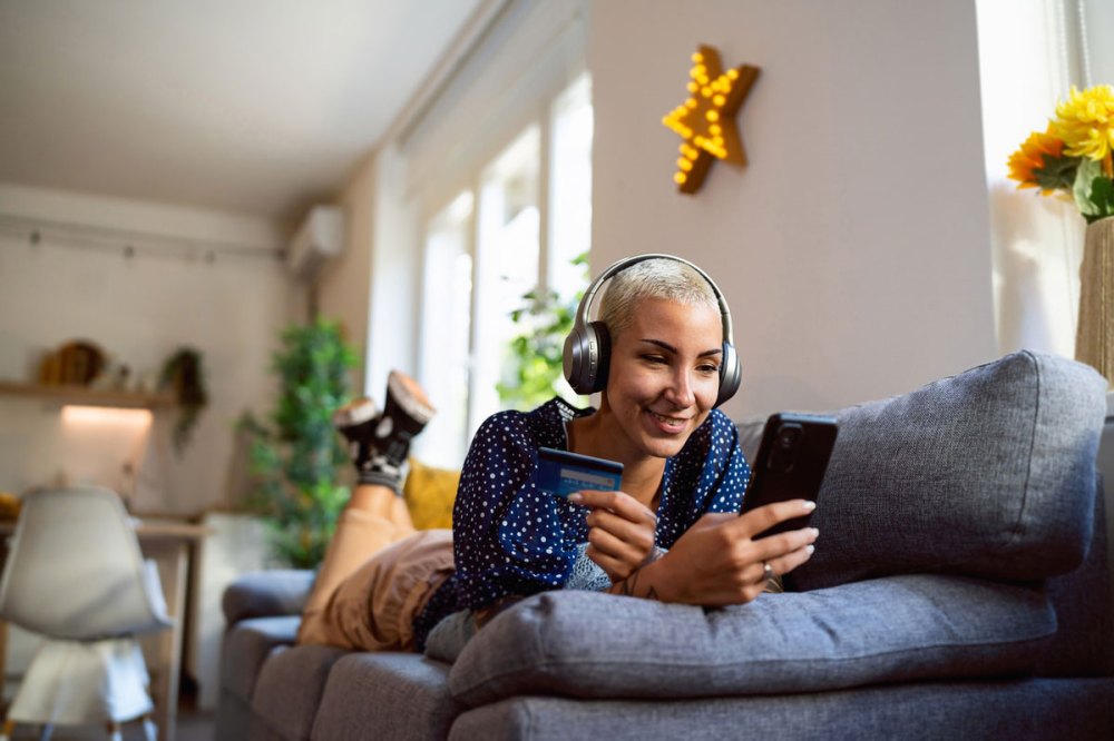 Woman with headphones on in her living room looking at her cell phone