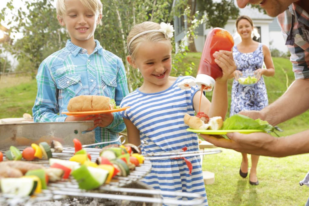 Family and kids having a BBQ grill meal outside in a garden