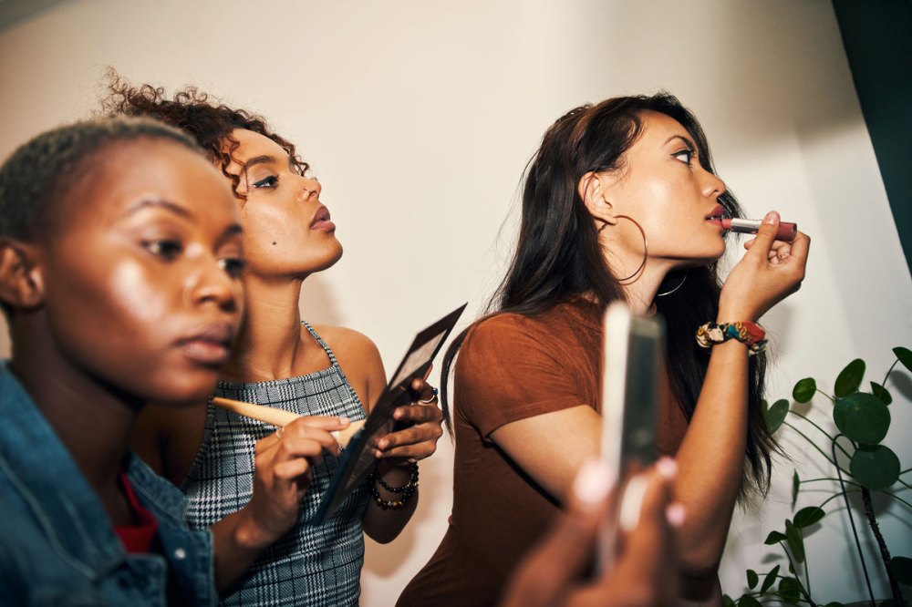 Three ladies putting on makeup