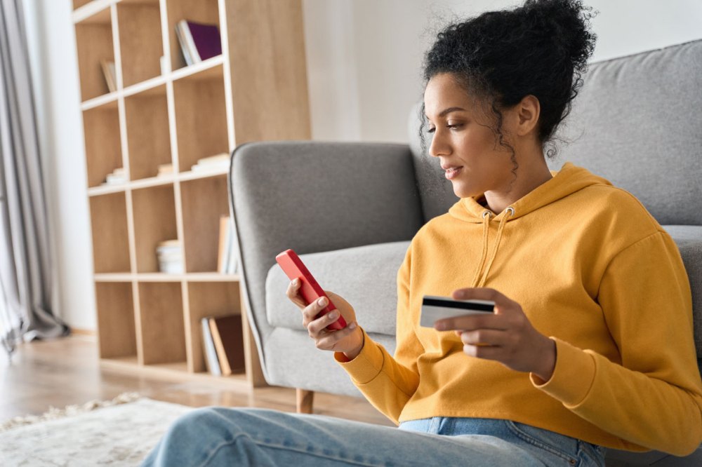 Woman in a yellow hoodie makes a purchase on her mobile phone