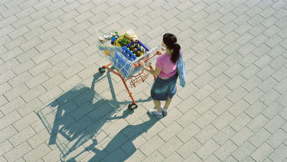 Birds eye view of a shopper pushing a shopping cart that is full outside of a store