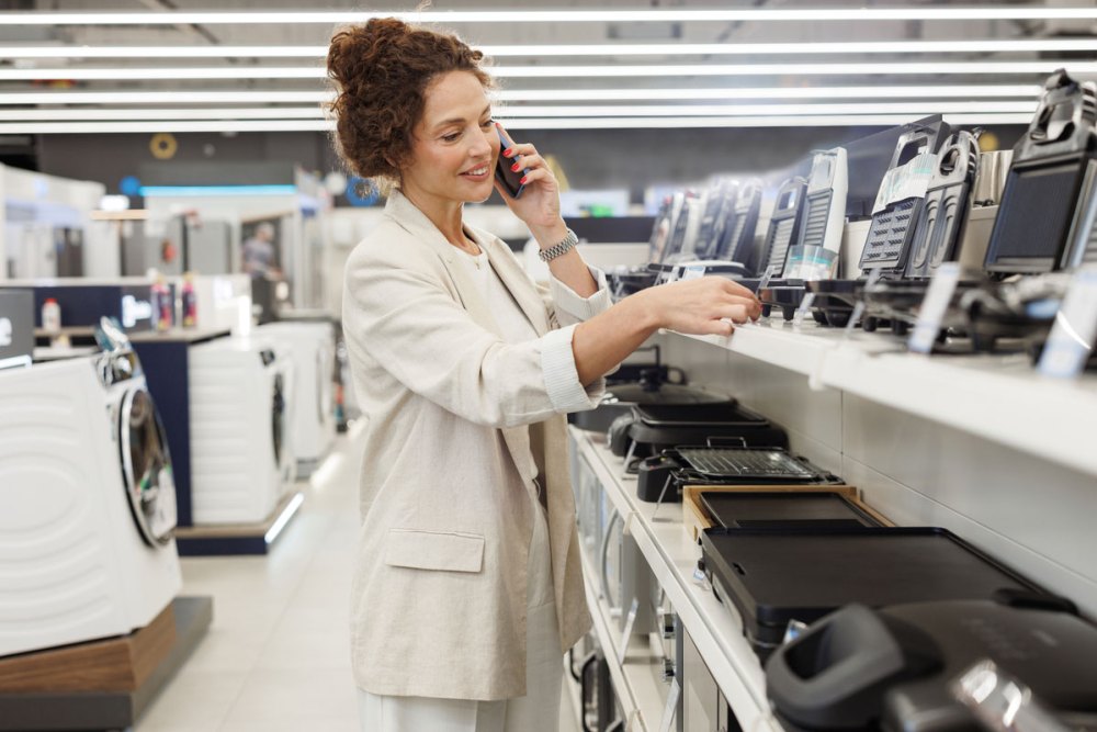 A Woman on a phone shopping in the small appliances section